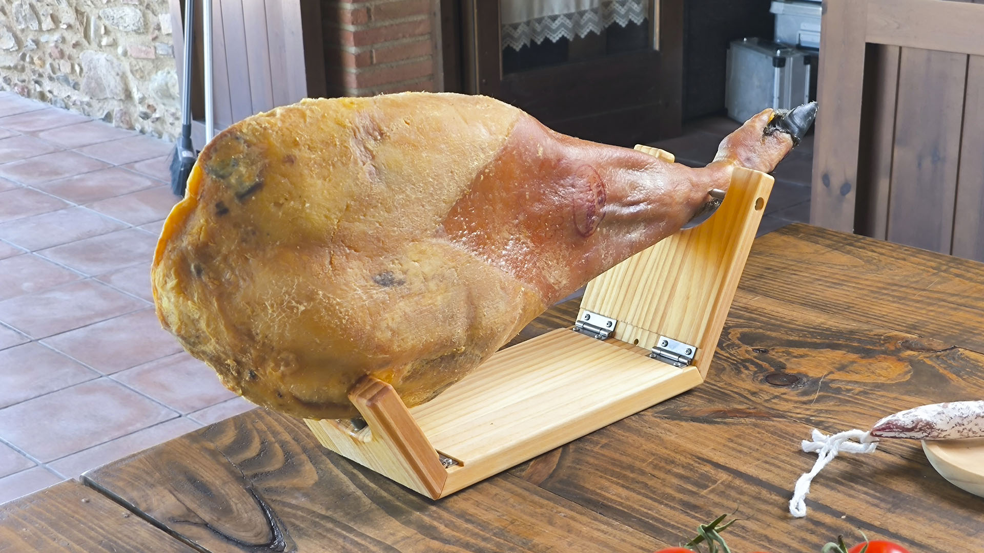 Jamón colocado sobre el jamonero plegable Kampé en una mesa de madera